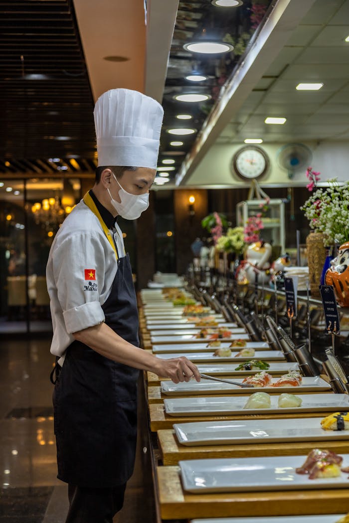 A skilled chef in uniform arranging dishes in a sophisticated restaurant setting.