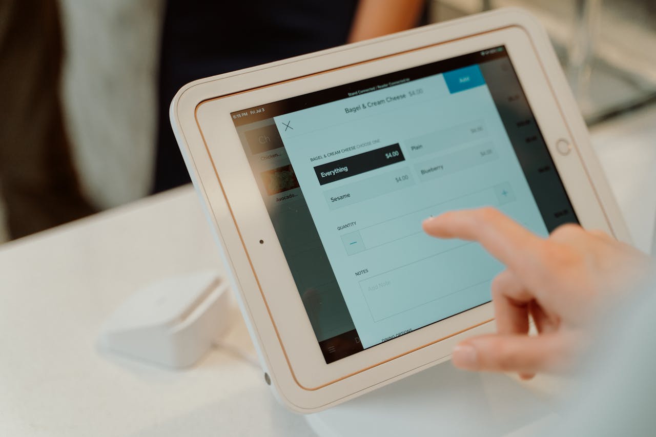 A person uses a tablet-based point-of-sale system by selecting options on a touchscreen device.