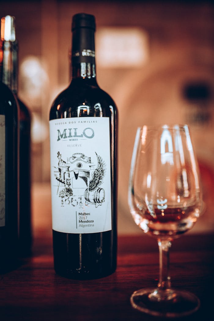 Vertical shot of a wine bottle and glass on a wooden table, perfect for dining themes.