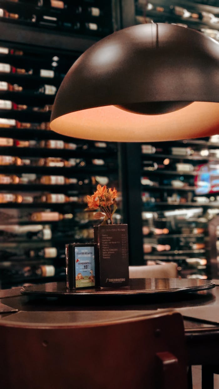 Services Warm ambiance in a wine cellar restaurant with elegant table setting under a stylish lamp.