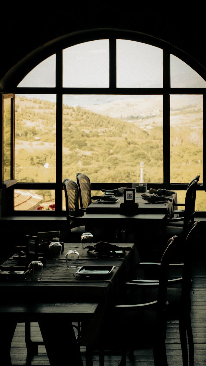 Services Elegant indoor dining with scenic mountain view through arched windows.